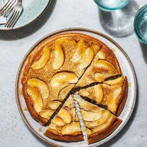 Baked apple pancake upside down on a large plate with four triangles cut.