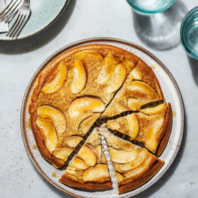 Baked apple pancake upside down on a large plate with four triangles cut.