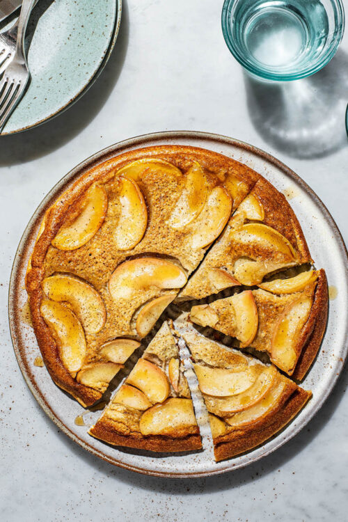 Baked apple pancake upside down on a large plate with four triangles cut.