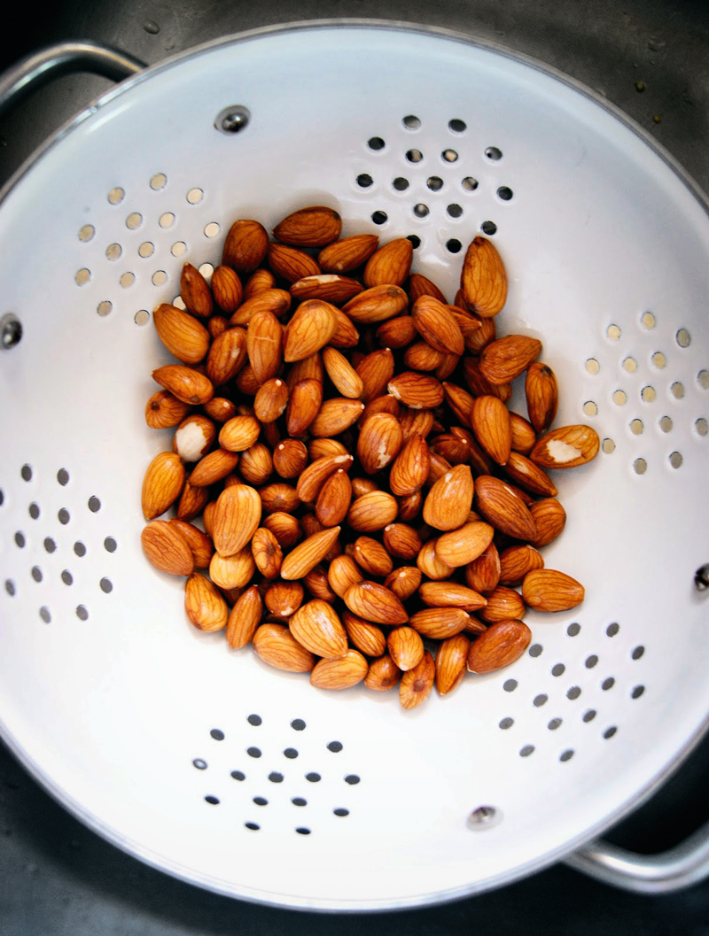 Soaked almonds in a white strainer.