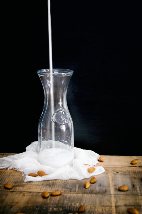 Almond milk being poured into a glass container.