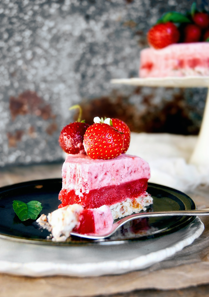 One slice of raw strawberry cake with a forkful removed.