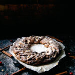 A bread wreath in front of a dark background.