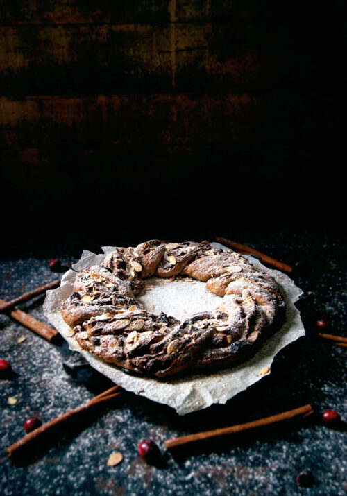 A bread wreath in front of a dark background.