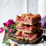 A stack of three crumble bars with flowers around.