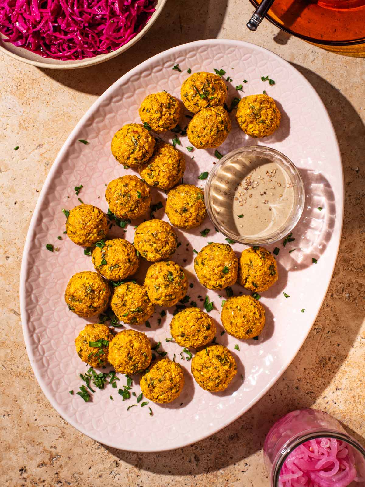 Small falafel on a light pink serving dish.
