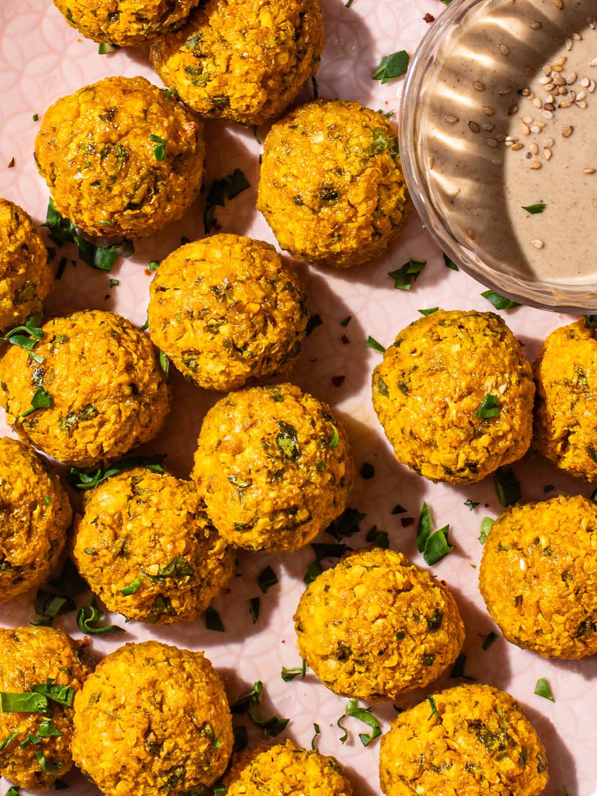 Close up of several orange falafel on a pink tray.