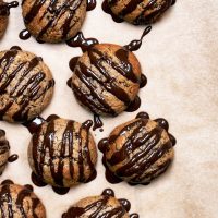 Vegan lebkuchen cookies with dark chocolate drizzle on baking paper.