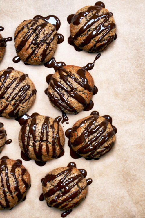 Vegan lebkuchen cookies with dark chocolate drizzle on baking paper.