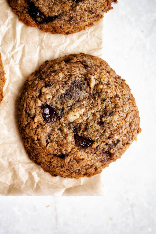 Close up of a chocolate chunk cookie on parchment paper.