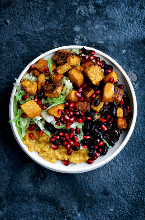 A rice bowl with winter squash, cabbage, and beans, top down view.
