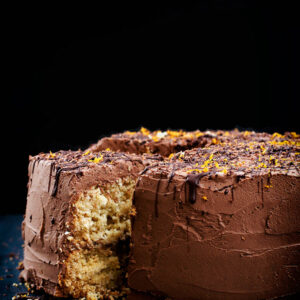 Coconut cake with chocolate frosting, front view, with one slice cut.