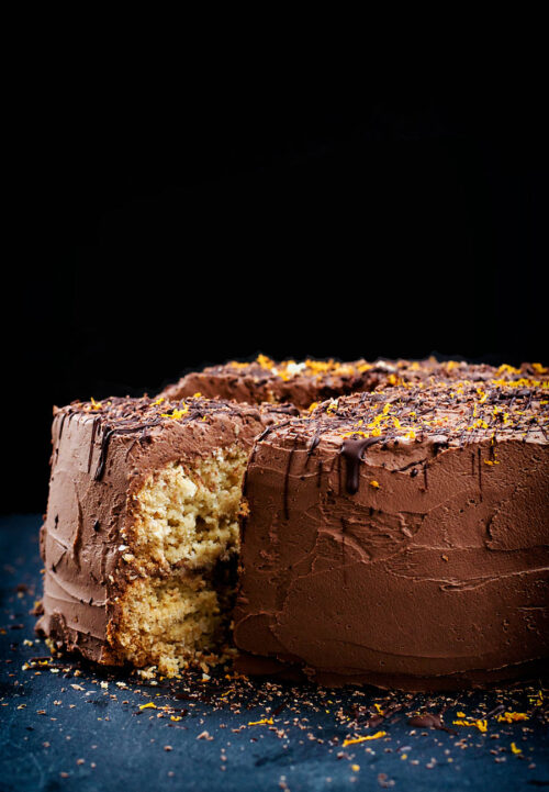 Coconut cake with chocolate frosting, front view, with one slice cut.