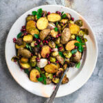 A plate of roasted potatoes and brussels sprouts with herbs.