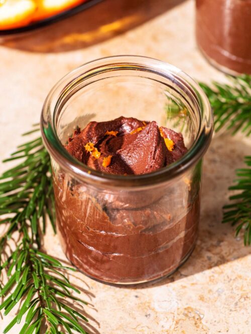 Chocolate mousse in small glass jars topped with orange zest.