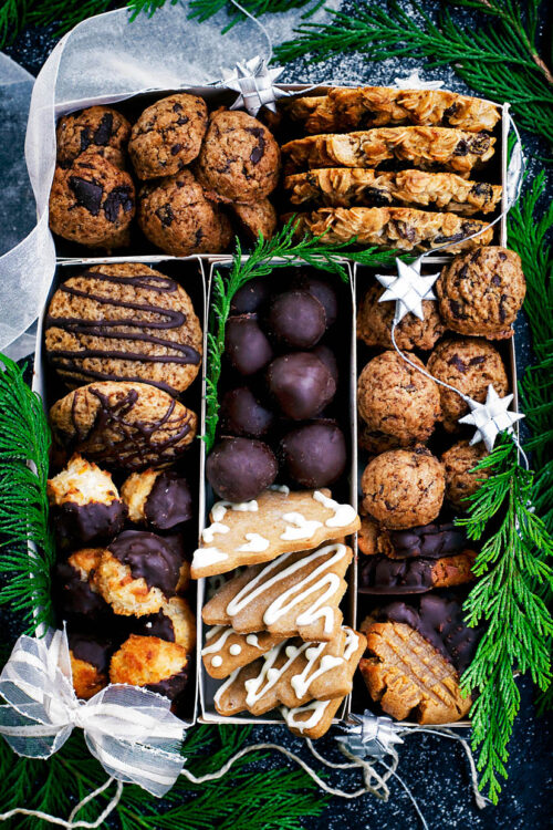 Several types of cookies arranged in a box with holiday decorations.