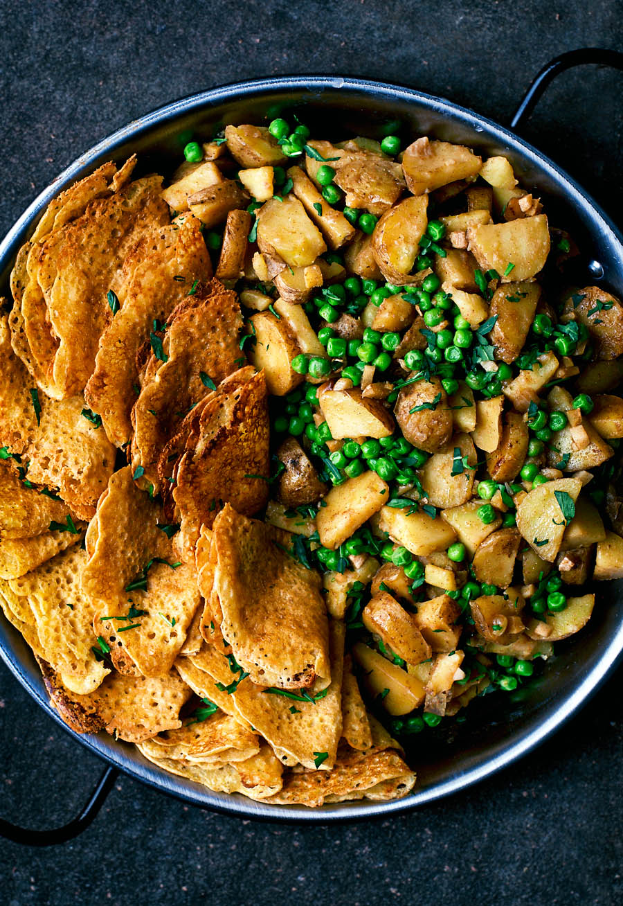 A large plate of potato pea curry with a side of homemade dosa.