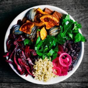 A top-down view of a bowl filled with vegetables, quinoa, and beans.