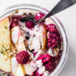 Close up of muesli in a glass jar with fruit toppings.