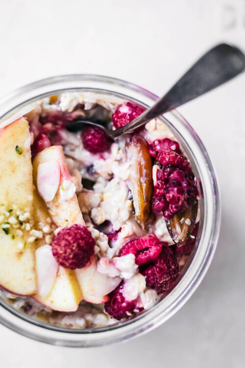 Close up of muesli in a glass jar with fruit toppings.