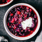 A bowl of red beet soup topped with yogurt.