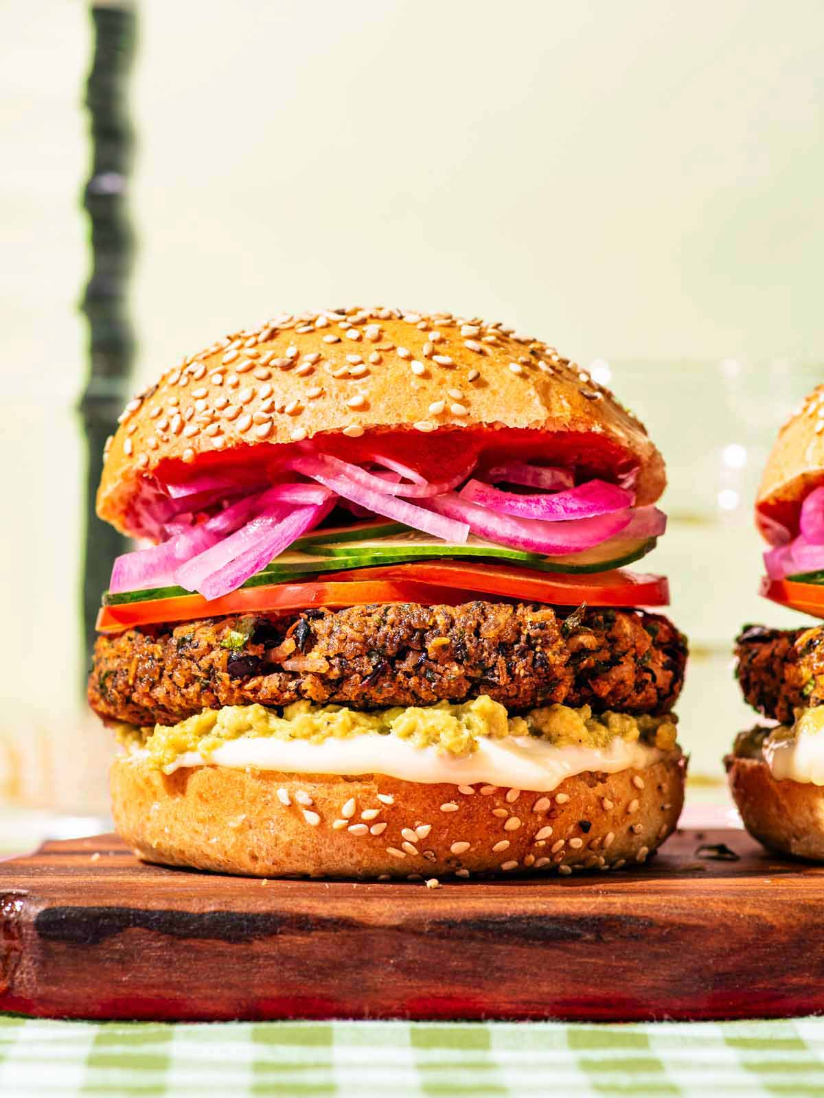 Close up of two black bean burgers on buns with various burger toppings.