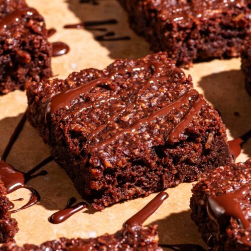 Brownies cut into squares with extra chocolate drizzled on top.