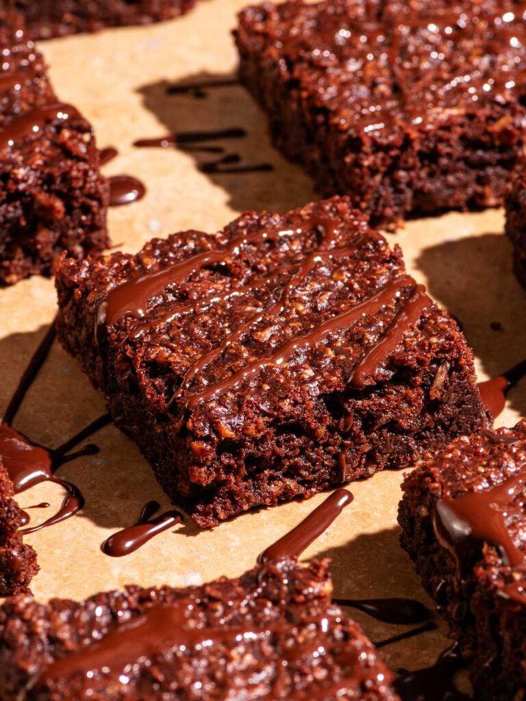 Brownies cut into squares with extra chocolate drizzled on top.