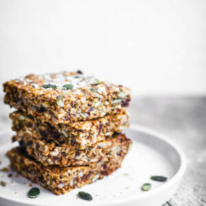 A stack of four carrot and seed granola bars on a small plate.