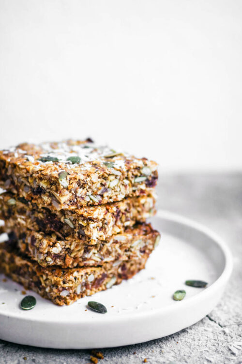 A stack of four carrot and seed granola bars on a small plate.
