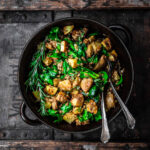 Potato salad in a large bowl with greens and rosemary sprigs.