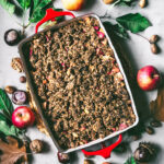 Apple crumble in a baking dish with autumn foliage around.