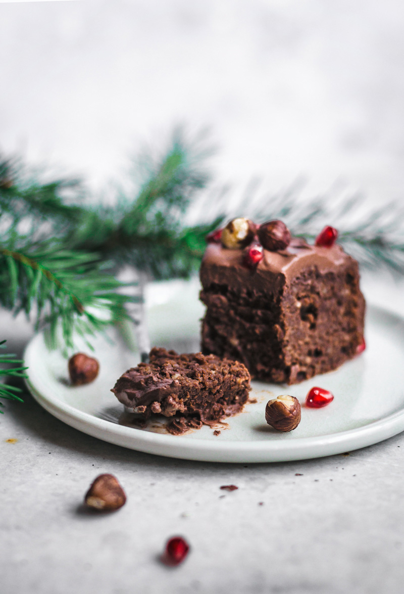 Slice of chocolate hazelnut cake topped with nuts and pomegranate.