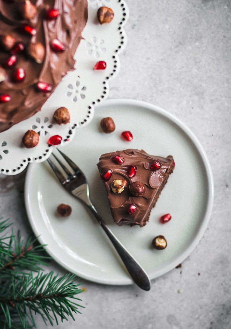 Slice of chocolate hazelnut cake topped with nuts and pomegranate.