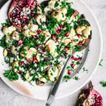 Cauliflower salad with herbs and pomegranate on a serving plate.
