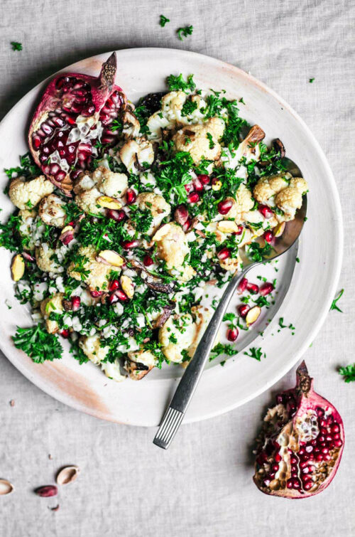 Cauliflower salad with herbs and pomegranate on a serving plate.
