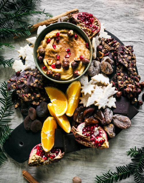 Cookie dough dip in a bowl on a platter with cookies and fruit.