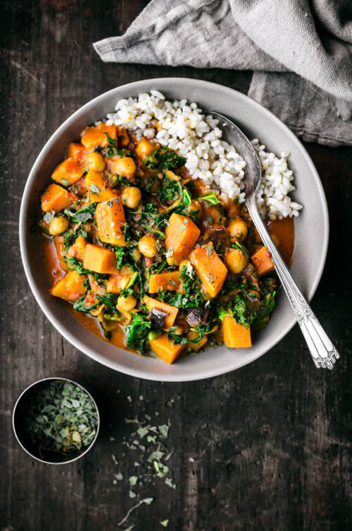 A bowl of sweet potato curry with rice in the bowl.
