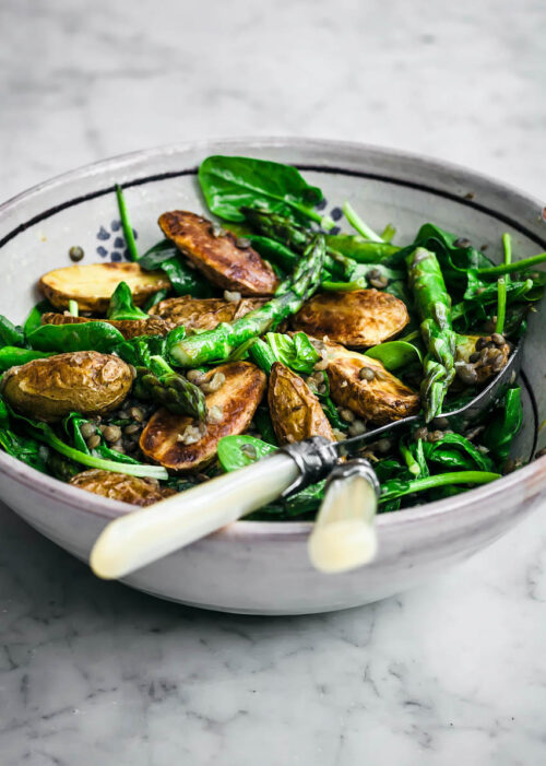 Potato asparagus salad in a large bowl with serving utensils.