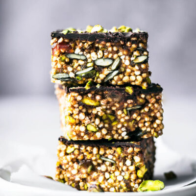 Three squares of a quinoa and seed bar stacked on a small plate.