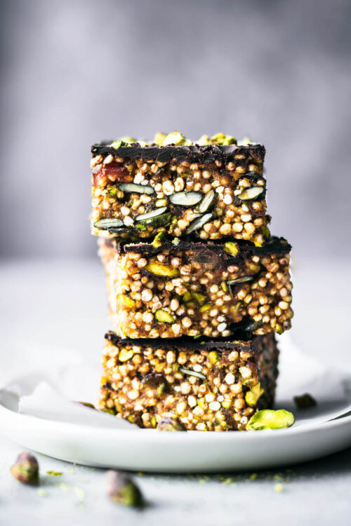 Three squares of a quinoa and seed bar stacked on a small plate.