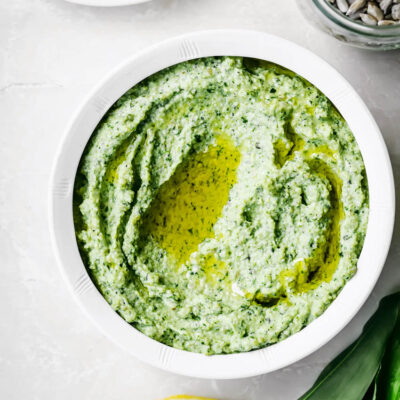 A small bowl full of light green pesto with oil.