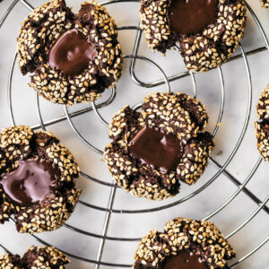 Several sesame-coated chocolate cookies on a wire rack.