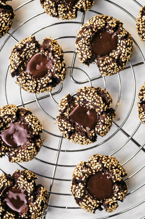 Several sesame-coated chocolate cookies on a wire rack.