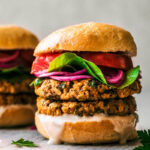 Close up of a veggie burger with double stacked patties and vegetable toppings.
