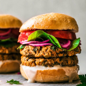 Close up of a veggie burger with double stacked patties and vegetable toppings.