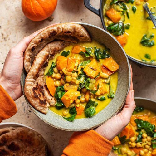 Woman's hands holding a bowl of curry.