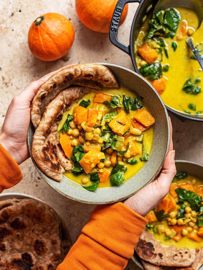 Woman's hands holding a bowl of curry.