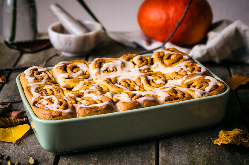 Glazed pumpkin cinnamon rolls in a baking dish.