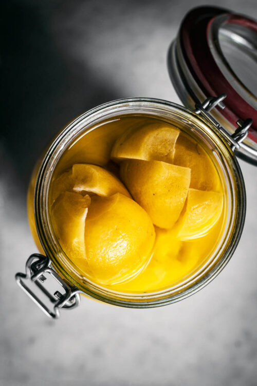 Top down view of a glass jar filled with preserved lemons.